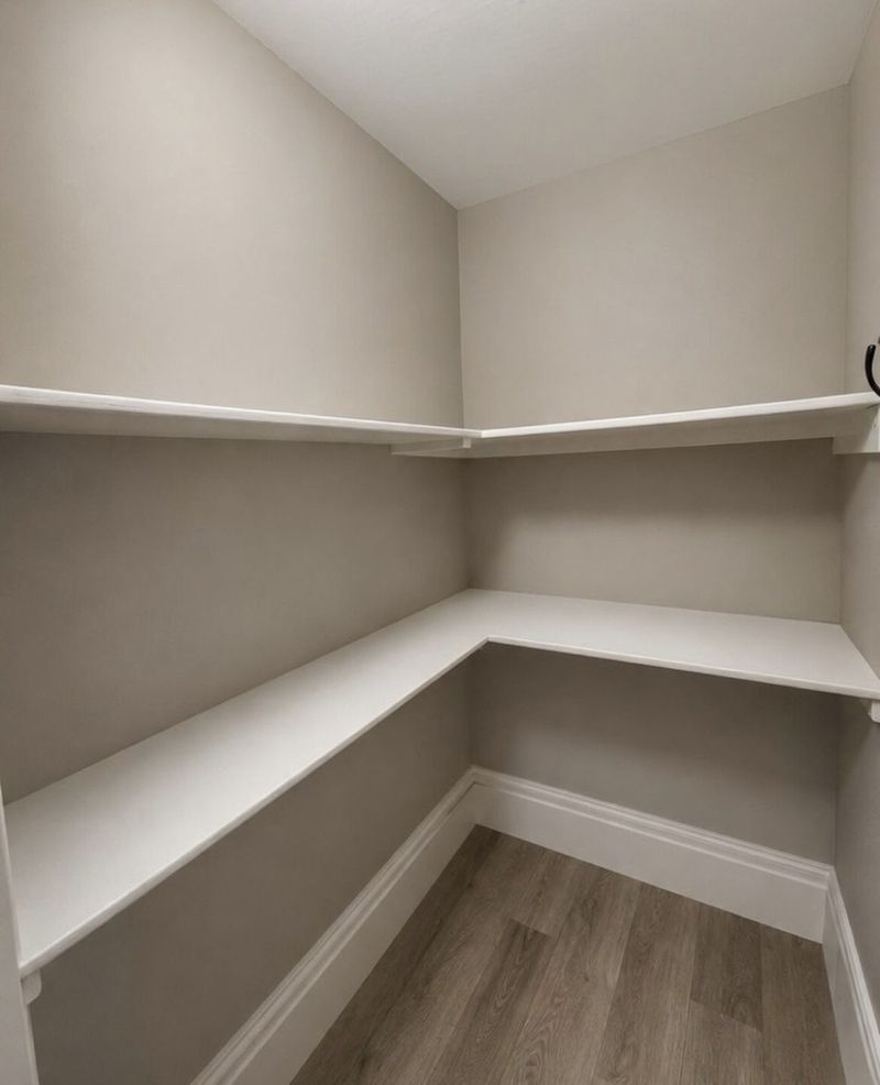 White fitted shelving built into the corner of a storage cupboard