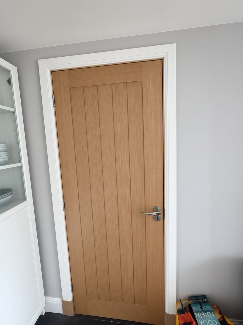 Oak cottage-style internal door hung in a white painted frame with a satin lever handle