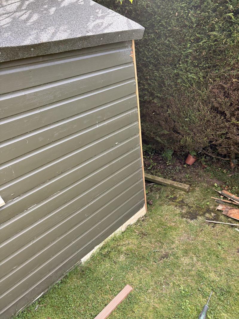 New corner trim and base board fitted to the end wall of a green painted shed