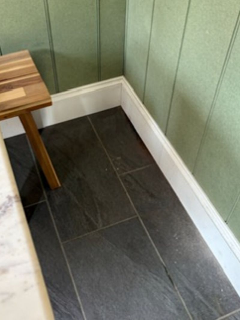 White painted skirting fitted around a panelled room with a slate-effect tiled floor